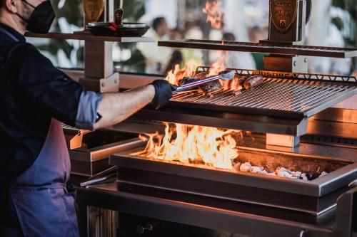 a man cooking food on a grill at Palacio de Sancti Petri, a Gran Meliá - The Leading Hotels of the World in Chiclana de la Frontera