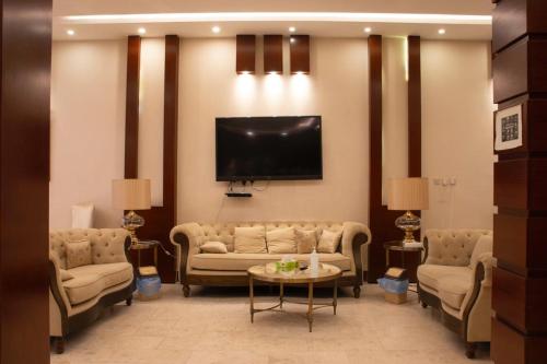 a living room with couches and a flat screen tv at Waqet AlFakhama Furnished Apartments in Tabuk