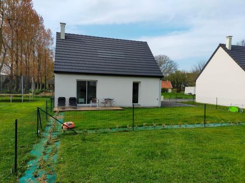 a white house with a black roof and a yard at Maison individuelle neuve plein pied avec terrasse et jardin clos 10minutes a pied de la plage in Quiberville