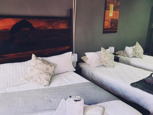 two beds in a room with white sheets and pillows at Ay Jay's Guesthouse in Bloemfontein