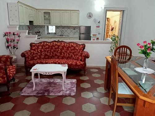 ein Wohnzimmer mit einem roten Sofa und einem Tisch in der Unterkunft Appartamento vacanze Le rose in Bosa