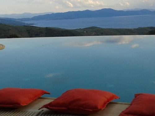 two red pillows on a table with a view of the water at Hotel Dryalos in Miléai