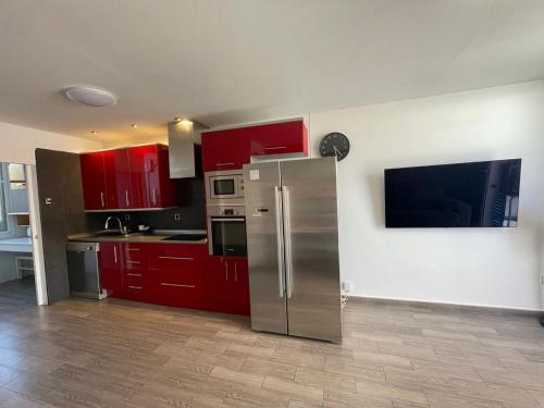 cocina con armarios rojos y nevera de acero inoxidable en Apartment Soleil Altamar en Playa de las Américas