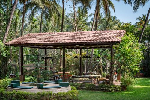 a pavilion with chairs and tables in a garden at Saffronstays Casa Del Palms, Alibaug - luxury pool villa with chic interiors, alfresco dining and island bar in Alibaug