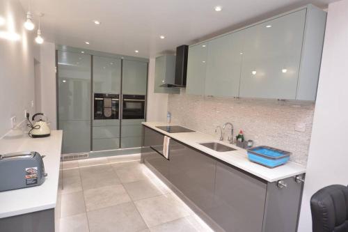 a kitchen with white cabinets and a sink at Luxury 5 Bedroom House with Free Parking on Site in Hornchurch