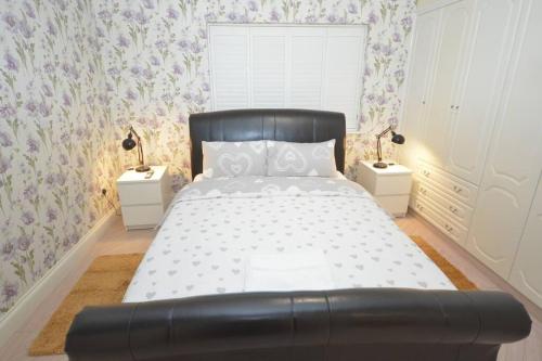 a bedroom with a large bed with two night stands at Luxury 5 Bedroom House with Free Parking on Site in Hornchurch