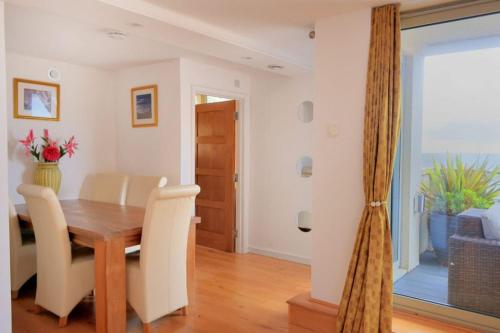 a dining room with a wooden table and chairs at Largigi offering two amazing panoramic sea front apartments in Lyme Regis