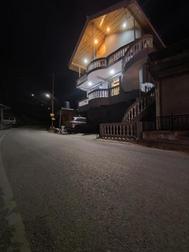 a building with stairs on the side of it at night at Doris Mountain Cabins Tirthan in Banjār
