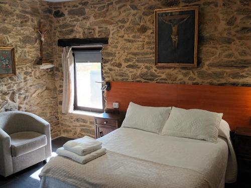 a bedroom with a bed and a chair and a window at Mercadoiro in Laje