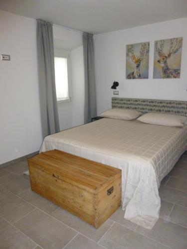 a bedroom with a large bed with a wooden box at Appartamento CADELAVE in Villa di Chiavenna