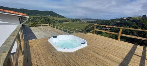 une baignoire assise sur une terrasse en bois dans l'établissement Villa Santorini Praia do Rosa com piscina e jacuzzi, à Praia do Rosa