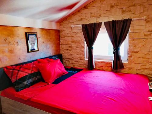 a red bed in a room with a brick wall at Apartments Obradovic in Krasici