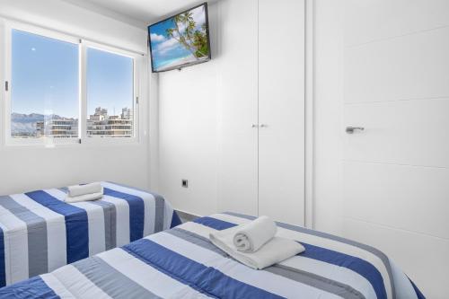 two beds in a room with a tv on the wall at Veracruz 20-E in Benidorm