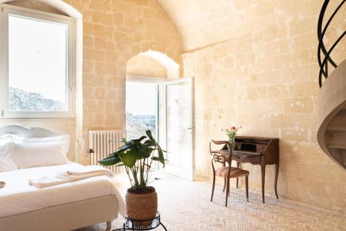 a bedroom with a bed and a table and a desk at Suite Santa Maria - L'Opera Dell'Architetto in Matera