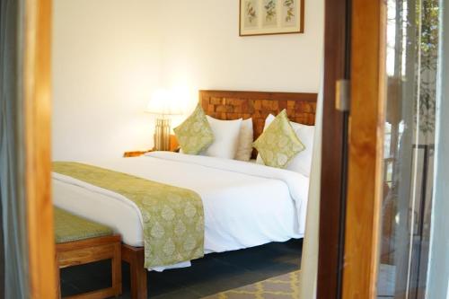 a bedroom with a large white bed and a chair at Saraca Resort & Spa Corbett in Garjia