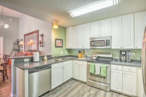a kitchen with white cabinets and stainless steel appliances at Cheery Condo with Community Pool and Waterslide! in Pine Bluff