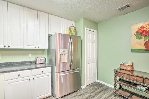 a kitchen with a stainless steel refrigerator and white cabinets at Cheery Condo with Community Pool and Waterslide! in Pine Bluff
