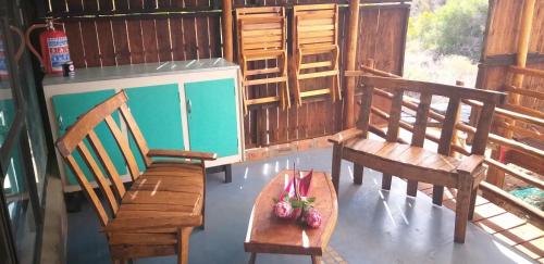 a room with two benches and a table with a bowl of fruit at Protea Lodge - Glamping in the Karoo in Barrydale