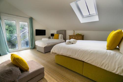 a bedroom with two beds with yellow pillows and a window at Largigi, Free Parking, Close to the Beach and Town Centre Rooms in Lyme Regis