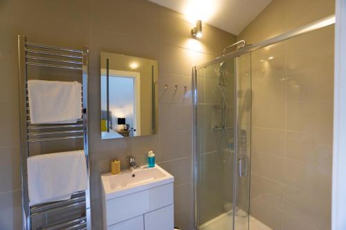 a bathroom with a shower and a sink and a mirror at Largigi, Free Parking, Close to the Beach and Town Centre Rooms in Lyme Regis