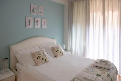 une chambre avec un lit blanc avec des oreillers et une fenêtre dans l'établissement Madeleine apartments - Appartamento di charme, à Milan