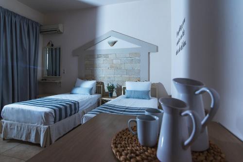 a hotel room with two beds and a table with cups at Le Palme in Malia