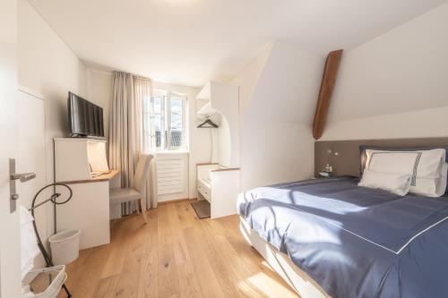 a small bedroom with a bed and a desk at Verena's Boutique Villa au lac in Sachseln