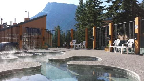 a patio with a pool with chairs and a mountain at Douglas Fir Resort & Chalets in Banff