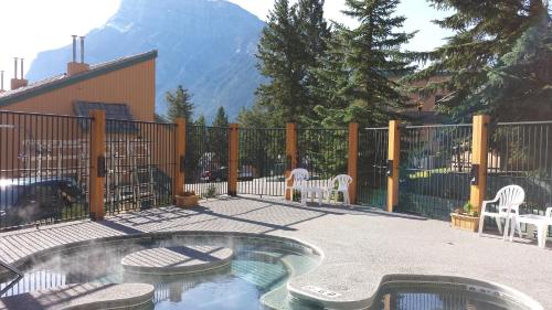 a patio with a pool and chairs and a fence at Douglas Fir Resort & Chalets in Banff