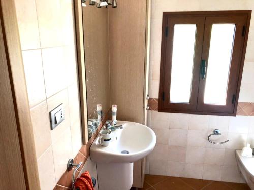 łazienka z umywalką, toaletą i oknem w obiekcie Villa Badessa w mieście Ostuni