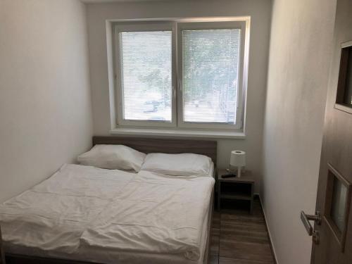 a small bedroom with a bed and two windows at Chata Relax in Bítov