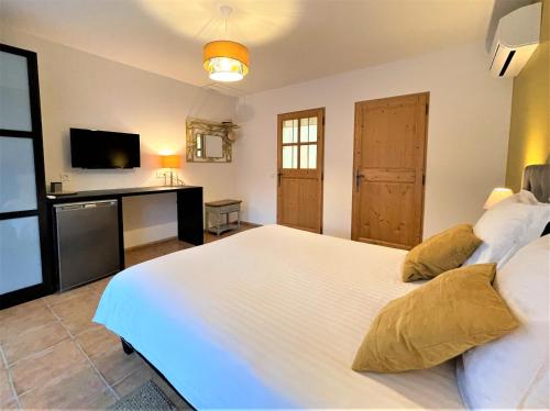 a bedroom with a large white bed and a television at Le Mas Carré Séguret in Séguret