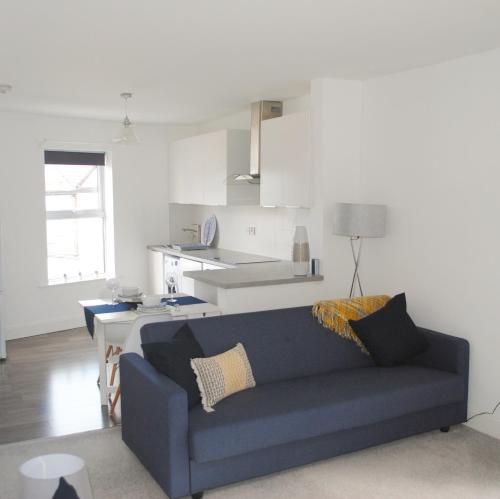 a living room with a blue couch and a kitchen at Bellevue Apartment in Bristol