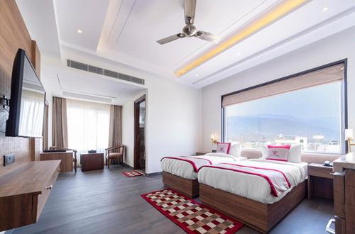 a bedroom with a large bed with a large window at Hotel Holy Vivasa in Rishīkesh