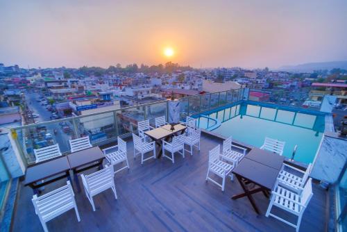 a balcony with tables and chairs and a view of a city at Hotel Holy Vivasa in Rishīkesh