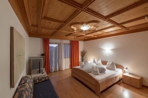 a bedroom with a bed and a wooden ceiling at Pension Apartments Klotznerhof in Schenna