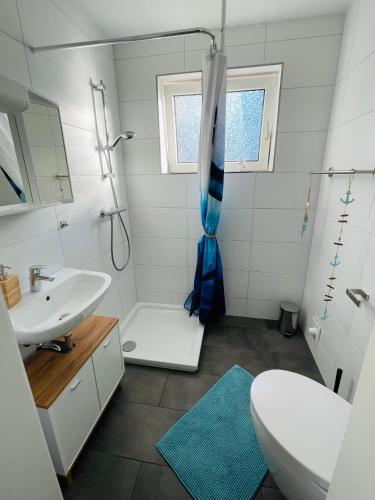 a white bathroom with a sink and a shower at Ferienwohnung „Deichgeflüster“ nahe der Nordsee in Marne