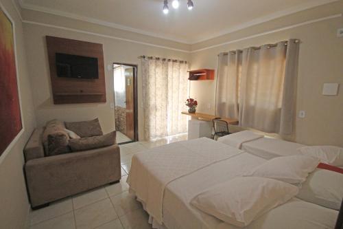 Recanto Villa REAL في أوليمبيا: غرفة نوم بسرير كبير وأريكة