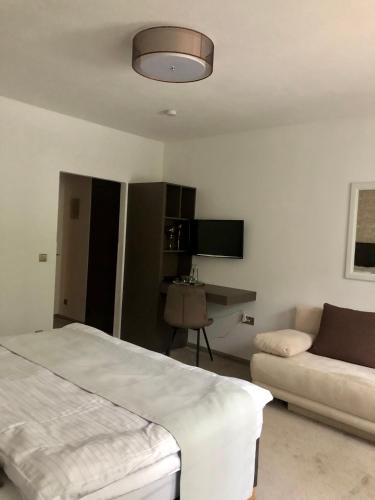 a white bedroom with a bed and a couch at Hotel Garni Klaret in Valtice