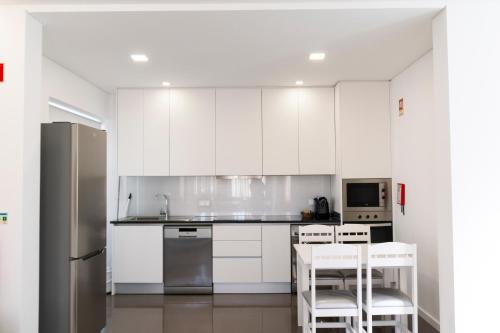 uma cozinha com armários brancos e electrodomésticos brancos em Casa dos Terraços Apartamentos em São Martinho do Porto