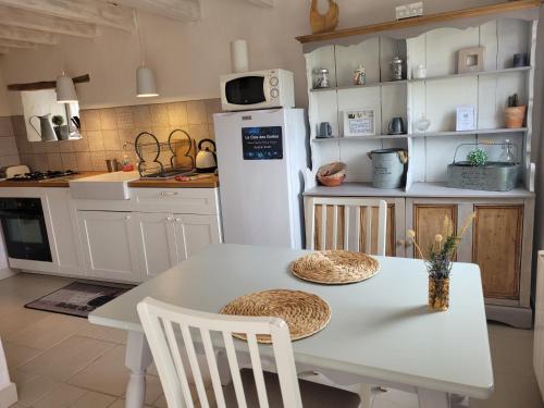 a kitchen with a white table and a white refrigerator at Le Clos Des Etoiles in Le Bugue