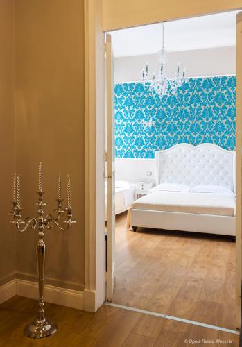 a bedroom with a white bed and a chandelier at Opera Relais in Messina
