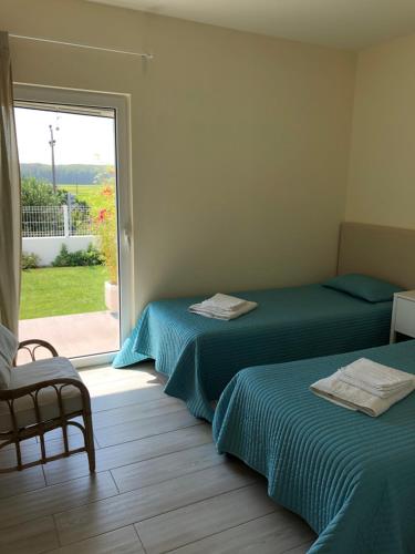 2 łóżka w pokoju z przesuwnymi szklanymi drzwiami w obiekcie Casa da Mondina Comporta w mieście Comporta
