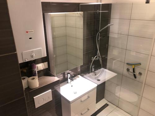 ein Bad mit einem Waschbecken und einer Dusche mit einem Spiegel in der Unterkunft Apartament Sikornik in Gliwice