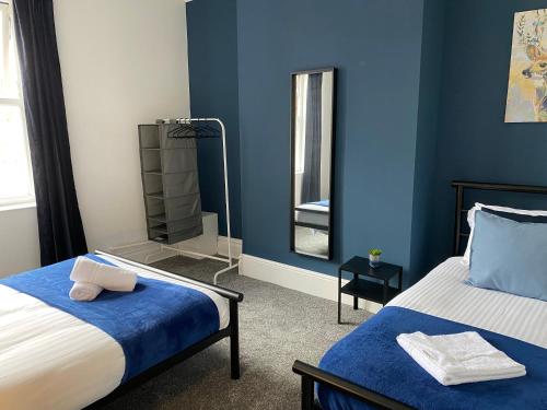 Dormitorio azul con cama y espejo en Rawling - Canny 2 bed flat close to Ncle free wifi & parking en Gateshead