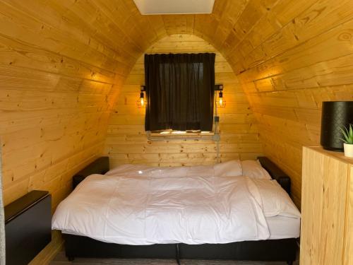Cama en una cabaña de madera con ventana en Tiny rooms @ camping val d'Or en Enscherange