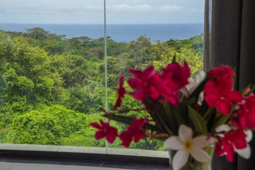 a vase of flowers in a window with a view of the ocean at Triângulo Noronha in Fernando de Noronha