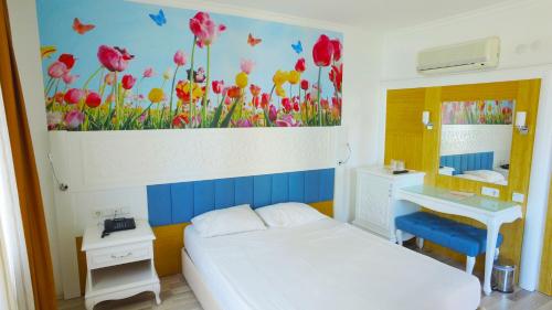 a bedroom with a bed and a sink and a painting of flowers at Eftalia Holiday Village in Konaklı