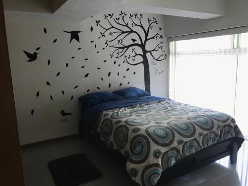 un dormitorio con un árbol con pájaros en la pared en Loft Aeropuerto, en Ciudad de México