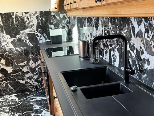 a kitchen with a sink and a black counter top at Chalet Chiemgau 90 qm 3 Zimmer Balkon in Übersee
